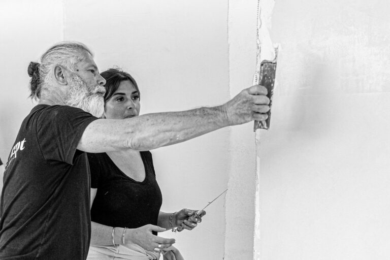 Le formateur du centre de formation qui accompagne une stagiaire dans l'application du mortier