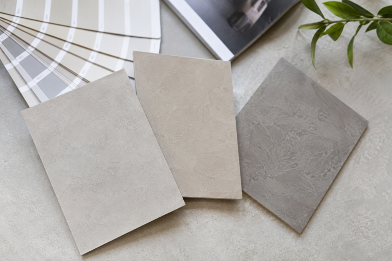 Échantillons d’enduits décoratifs aux teintes beige et grise accompagnés d’un nuancier de couleurs.